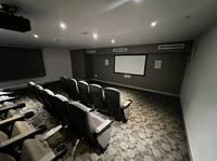 a cozy home theater room featuring multiple rows of comfortable reclining seats, a large projector screen, and subtle recessed lighting, perfect for immersive movie experiences in a modern residential setting.